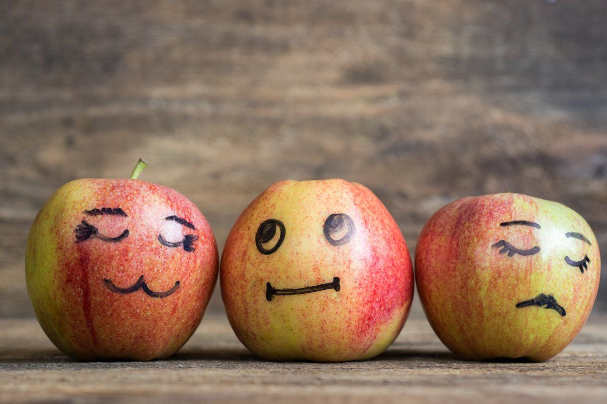 trzy jabłka z narysowanymi buźkami pokazującymi uczucia