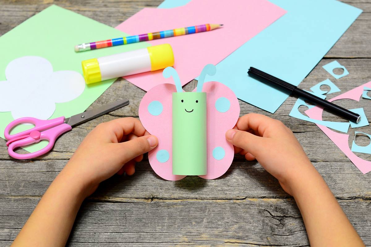 Dziecko robi motylka z rolki po papierze i z kolorowego papieru